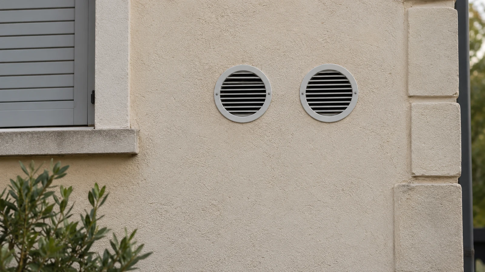 Deux grilles rondes côte à côte sur une façade, sans climatiseur ni unité extérieure visibles.