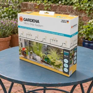 Boîte du kit GARDENA 13400-20 posée sur une table de jardin avant installation, pour arroser des pots aux besoins différents.
