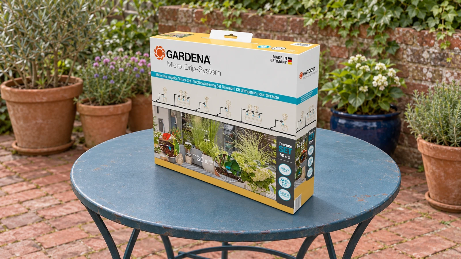 Boîte du kit GARDENA 13400-20 posée sur une table de jardin avant installation, pour arroser des pots aux besoins différents.