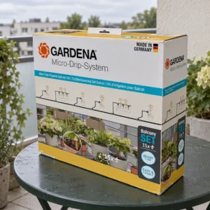 Boîte du kit GARDENA 13401-20 près de pots groupés et d’un robinet de balcon, pour préparer un arrosage goutte-à-goutte.
